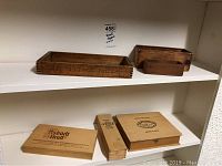 Lower shelf featuring 4 wooden boxes with various vintage printed logos and branding, different closure styles.