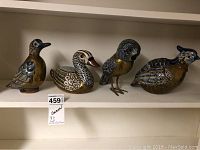 Front view of four decorative metal wildlife bird figurines arranged on a shelf.
