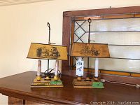 Pair of vintage metal lamps on wooden surface, showing overall design and placement.