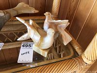 Pair of onyx bird sculptures positioned with one bird facing forward and one sideways on a glass table, showing shape, size, and polished surface.
