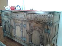 Front view of the carved wooden buffet showcasing drawers and cabinet doors with decorative carvings and wooden knobs.