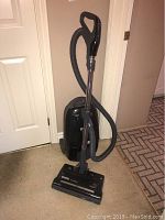 Full view of black Kenmore upright vacuum with grey hose and handle.