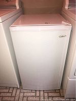Photo of the front of the closed Salton mini vertical freezer showing white exterior and brand logo