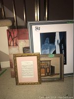 Group photo of four framed art pieces: large photograph, music sheet, and two paintings.
