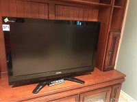 Front view of Toshiba Regza 42-inch flatscreen TV on wooden shelf with attached stand and visible Toshiba logo.