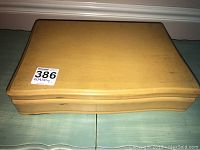 Closed wooden storage casket with a simple curved design.