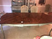 Front view of Thomasville dining table with one leaf inserted in a dining room setting, showing overall form.