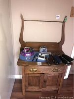 Front view of antique pine washstand with various small items placed on top, including eyeglasses cases and a floral tin