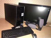 Overall setup showing desktop tower, monitor, keyboard and speakers on table