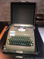 Vintage Smith Corona typewriter with dark green and cream keys inside a black carrying case.