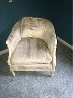 Front view of upholstered tub chair showing oval back, seat, and wooden legs with painted white finish, fabric visibly stained and worn.