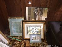 Six framed prints of various sizes arranged against wooden paneled wall, showing largest print in back and smallest in front, minor scratches visible on frame edges