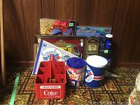 Lot containing Blue Jays memorabilia, beer signs, Coca-Cola carrier, and more on patterned carpet against wood panel backdrop.