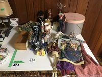 Overview of the lot including jewelry stand, ceramic trinkets, figurines, vintage hat box, and textiles