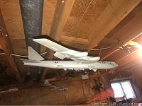 Model planes hanging from basement wooden ceiling beams, including a large white and gray USAF bomber model.