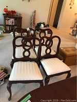 Four mahogany dining chairs arrangement showing carved loop backrests and upholstered cream striped seats.