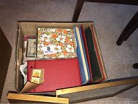 Box containing 4 albums including a floral-patterned box album and other binder albums with stamp collections inside.
