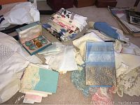 Photo of assorted vintage linens spread on floor, showing multiple folded pieces with detailed embroidery and lace features