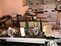 View showing assorted candles and candle holders on countertop with kitchen background
