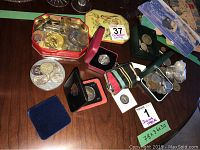 Overview of all coins in various containers including tins, small boxes, and pouches on a table