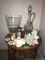 Photo of crystal pinwheel jug with stopper, 10-inch glass vase, and six small colorful decorative animal figurines on a wooden table.