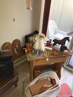 View showing wooden goose wall plaques, wooden table with various decorative wooden and ceramic items including a horse and duck figurine, ceramic swan, and wooden tray.