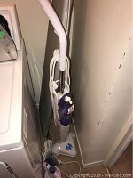 Floor steamer and portable handheld steamer seen together from a side angle, showing their general shape, cords, and handles.