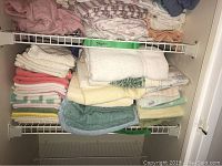 Shelf with stacked bath towels in multiple colors and sizes showing condition and assortment