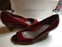 Side view of the pair of red patent wedge heels showing the shape, wedge heel and peep toe style with the Worthington box in the background.
