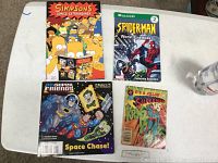 Four paperback comic books displayed on a table: Simpsons Comics Extravaganza, Spider-Man Worst Enemies, Superman vs Kryptonite, and Super Friends Space Chase.