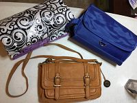 Photo showing a tan leather crossbody bag by The Sak, a medium-large blue cosmetics bag, and a large reusable grocery bag with swirl patterns.
