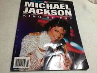 Front cover of the paperback book showing Michael Jackson in a white sparkly jacket holding a microphone, titled 'Michael Jackson King of Pop'.