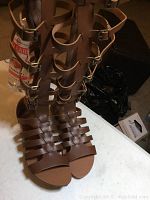 Front view of chestnut gladiator boots showing multiple straps, buckles, and open toe design.