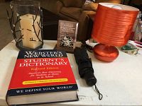 Overview of lot including mini orange lamp, mini umbrella, tall glass candle holder, friendship plaque, Webster's dictionary, and repellent coils.