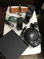 Overview of the lot showing all items including the iron, wall racks, burner stove, canisters, wine opener, and small black device.