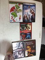 Photo of all DVD cases displayed on a white surface showing collection of 12 titles including Grinch, Tomorrowland, Twelve, Ancient Evil, and a multi-movie Thrills and Chills collection.