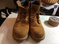 Front view of pair of lightly used Timberland men's boots in wheat color on table surface