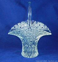 Clear glass bridal basket on blue background showing full front view with handle.