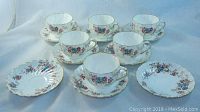 Eight Crown Staffordshire Elizabethan cups and matching saucers arranged on a light cloth background showing floral and gold detailing.
