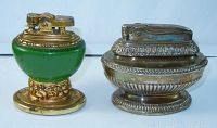 Front side view showing both vintage table top lighters with distinctive brass and green design, placed side by side