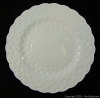 Full front view of the white ceramic chop plate with scalloped edges and embossed daisy pattern.