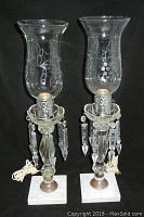 Pair of lamps with etched glass shades, hanging crystals, and white marble bases shown in full front view.