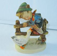 Front angle of the figurine showing the boy leaning over the fence looking at the goose with detailed hand-painted colors.