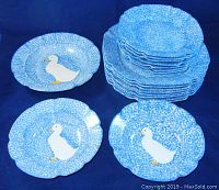 Photo showing multiple plates and bowls stacked together clearly depicting blue stipple spongeware pattern with white ducks on the plates.