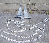 Photo showing galvanized boat anchor laid flat on the ground with the 20-foot galvanized chain fully extended and attached.