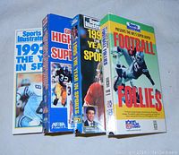 Four VHS tapes with colorful cardboard sleeves featuring football players and Sports Illustrated branding.