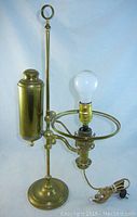 Full view of the electrified brass antique Kleeman student oil lamp, showing bulb and oil reservoir