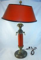 Full view of vintage metal table lamp with red cylindrical body and reddish tapered metal shade with perforated top and finial