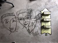 Four wire sculpture faces and a metal wall-mounted storage piece with three storage boxes laid out on a concrete floor.