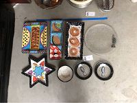 Top view of nine colorful serving platters and bowls arranged on a flat surface showing fish and abstract designs